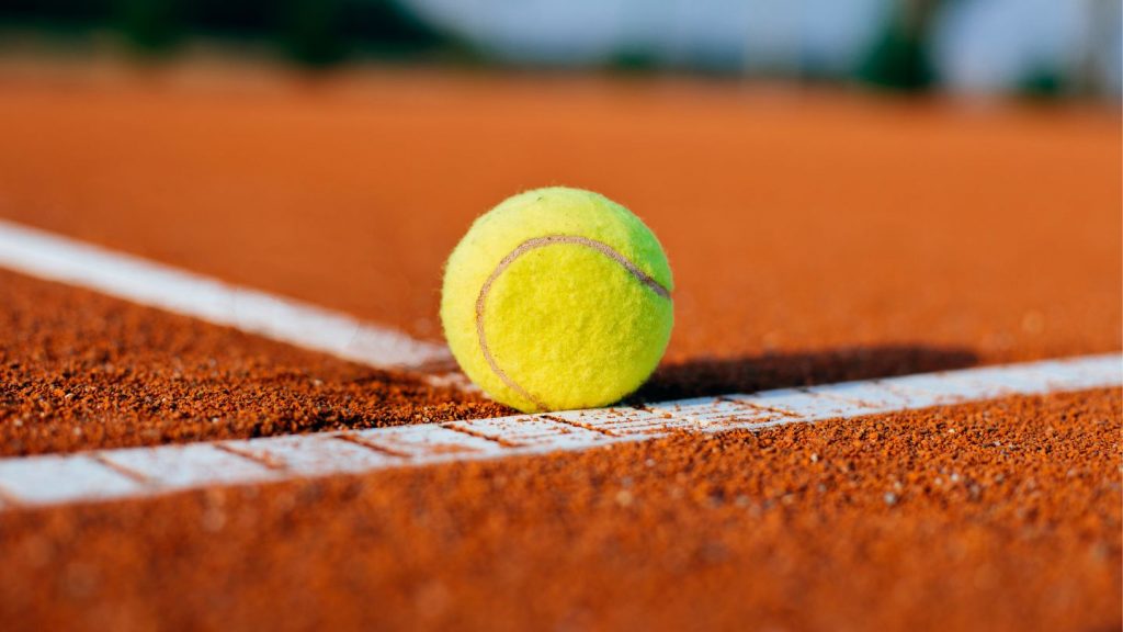 Yellow Tennis Ball on a Red Clay Court 